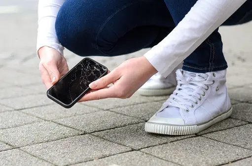 Persona levantando su celular con la pantalla rota tras una caída