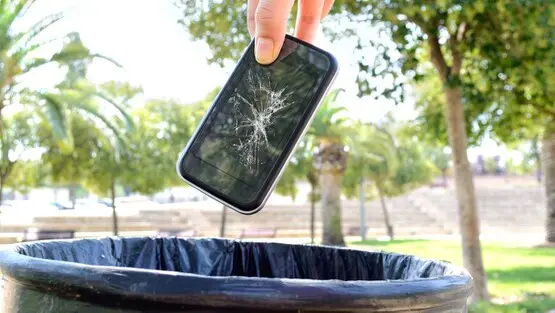 Celular con pantalla rota a punto de descartarse en un tacho de basura