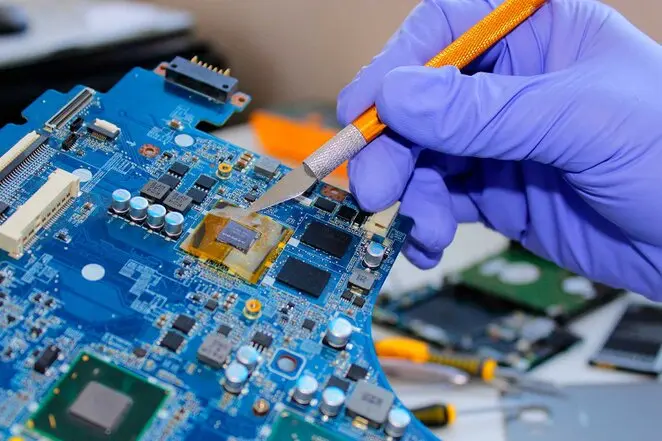 Técnico reparando la placa base de una notebook con soldadura de precisión