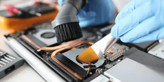 Técnico limpiando el interior de una notebook y cambiando la pasta térmica