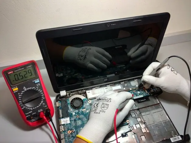 Técnico probando la placa base de una notebook con multímetro