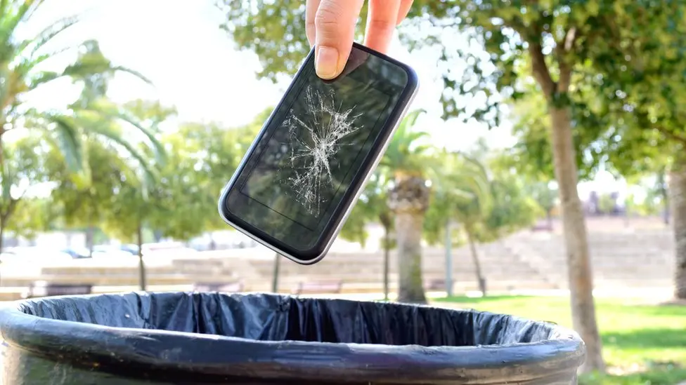 Mano por tirar un celular con la pantalla rota a un tacho de basura