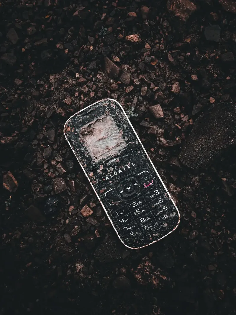 Celular Alcatel sobre grava, mostrando su logo de marca