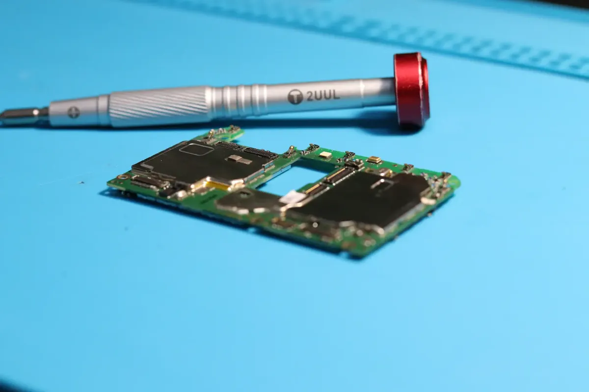 Placa de un celular sobre una mesa de trabajo azul, lista para reparación