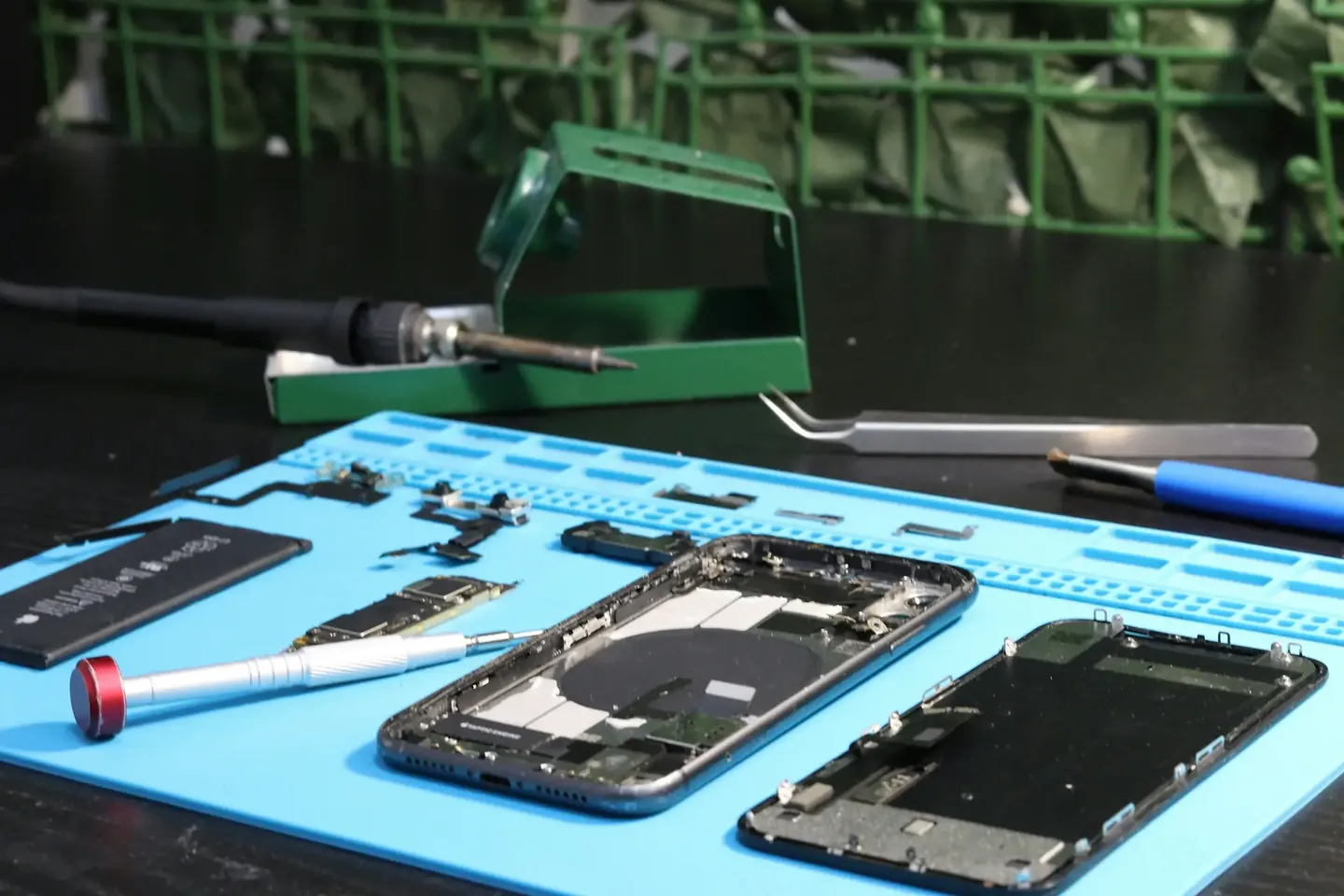Mesa de trabajo con herramientas de microsoldadura y un celular desarmado durante una reparación en GRUPOSERVICE