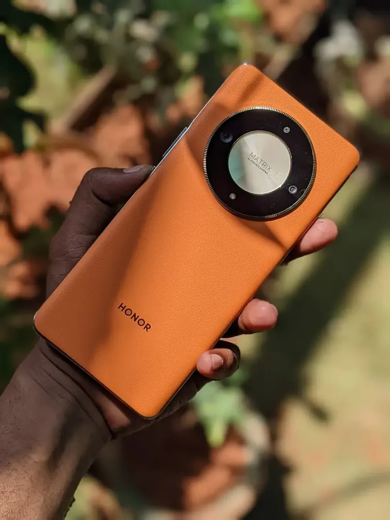 Celular Honor color naranja con el logo de la marca visible, sostenido en la mano