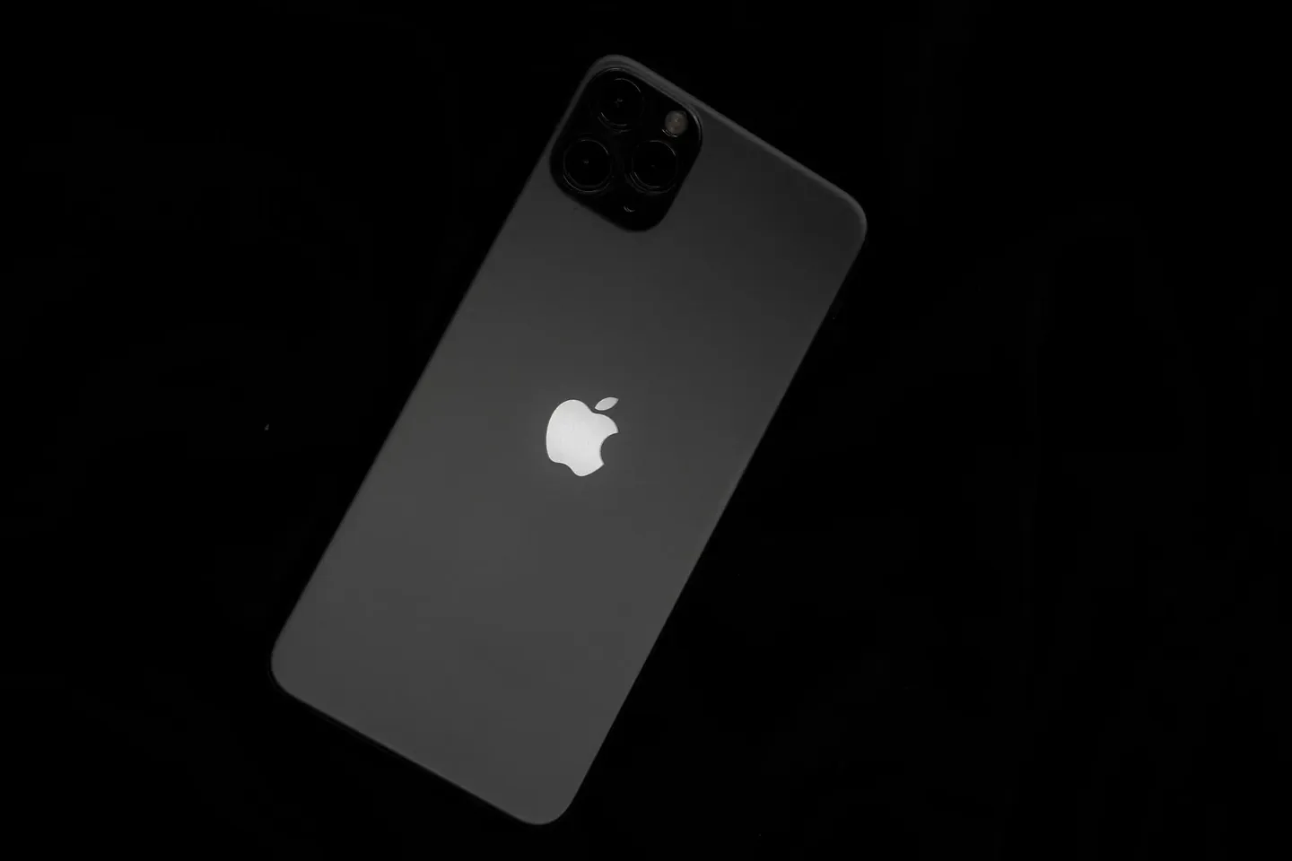 Parte trasera de un iPhone en fondo oscuro, con el logo de Apple iluminado