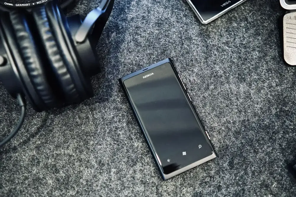 Celular Nokia junto a auriculares sobre una superficie gris