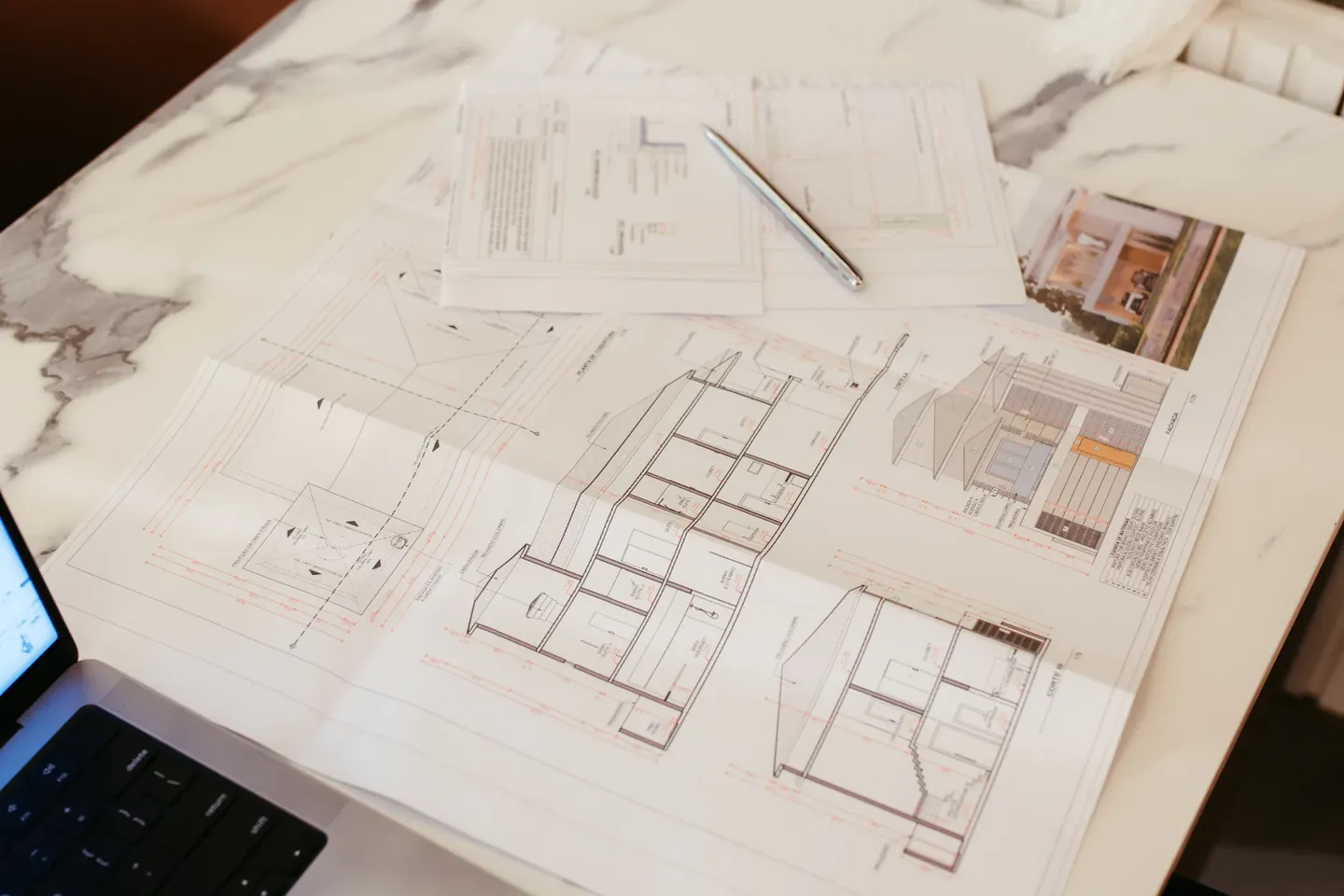 Escritorio de un estudio profesional con planos y notebook, representando el diseño de un sitio web para profesionales