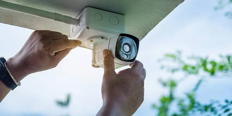 Técnico instalando una cámara de seguridad en el alero de una casa