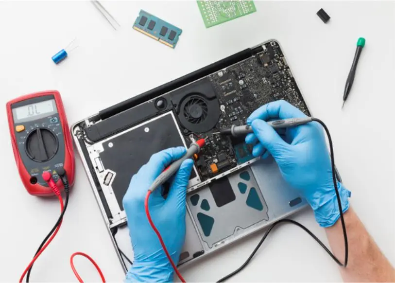 Técnico diagnosticando la placa de una notebook con multímetro